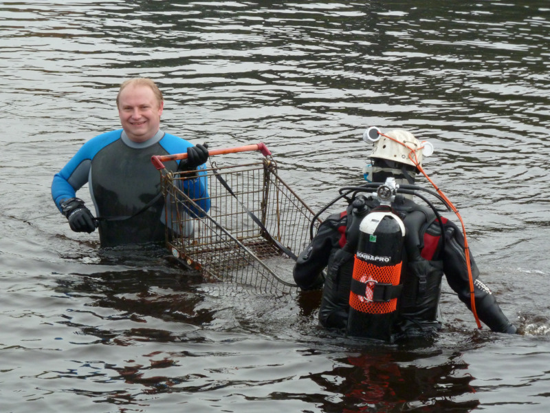 A man holding a trolley in a river with a scuba diver